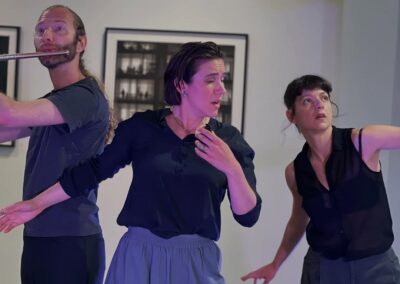 Three performers in a modern dance piece, one playing flute.